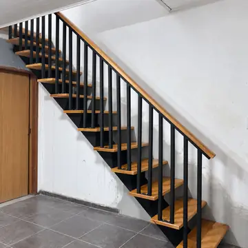 Escada reta com guarda-corpo de barras verticais pretas e corrimão de madeira